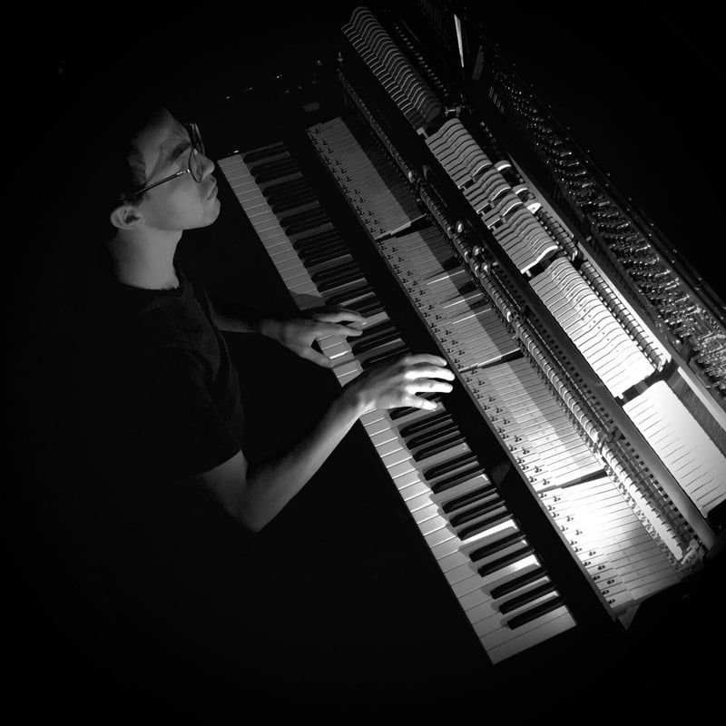 Mauricio Trabanino playing piano in a darkened studio